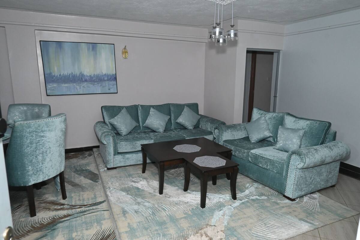 Ein Wohnzimmer mit einem Ecksofa, zwei Sesseln, einem Couchtisch und einem Bild an der Wand.