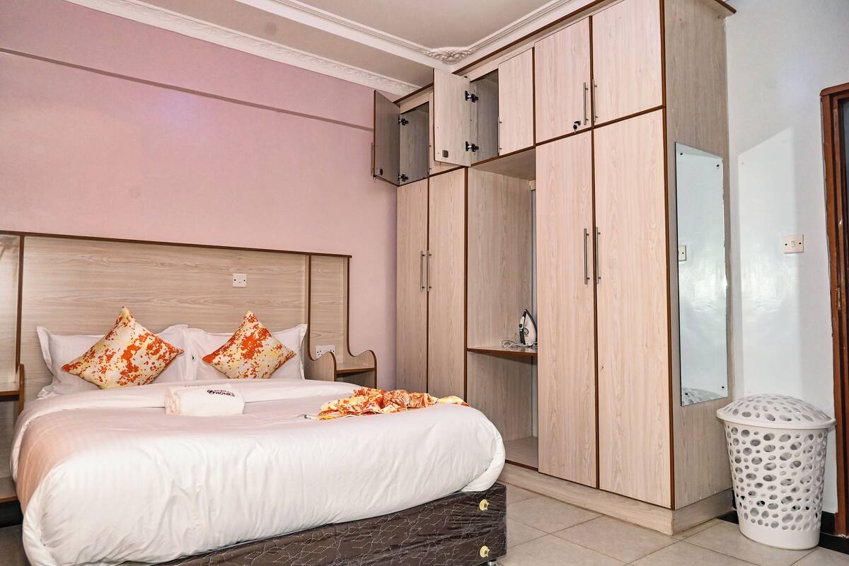 Ein Schlafzimmer mit Bett, Kleiderschrank, Spiegel und Mülleimer.