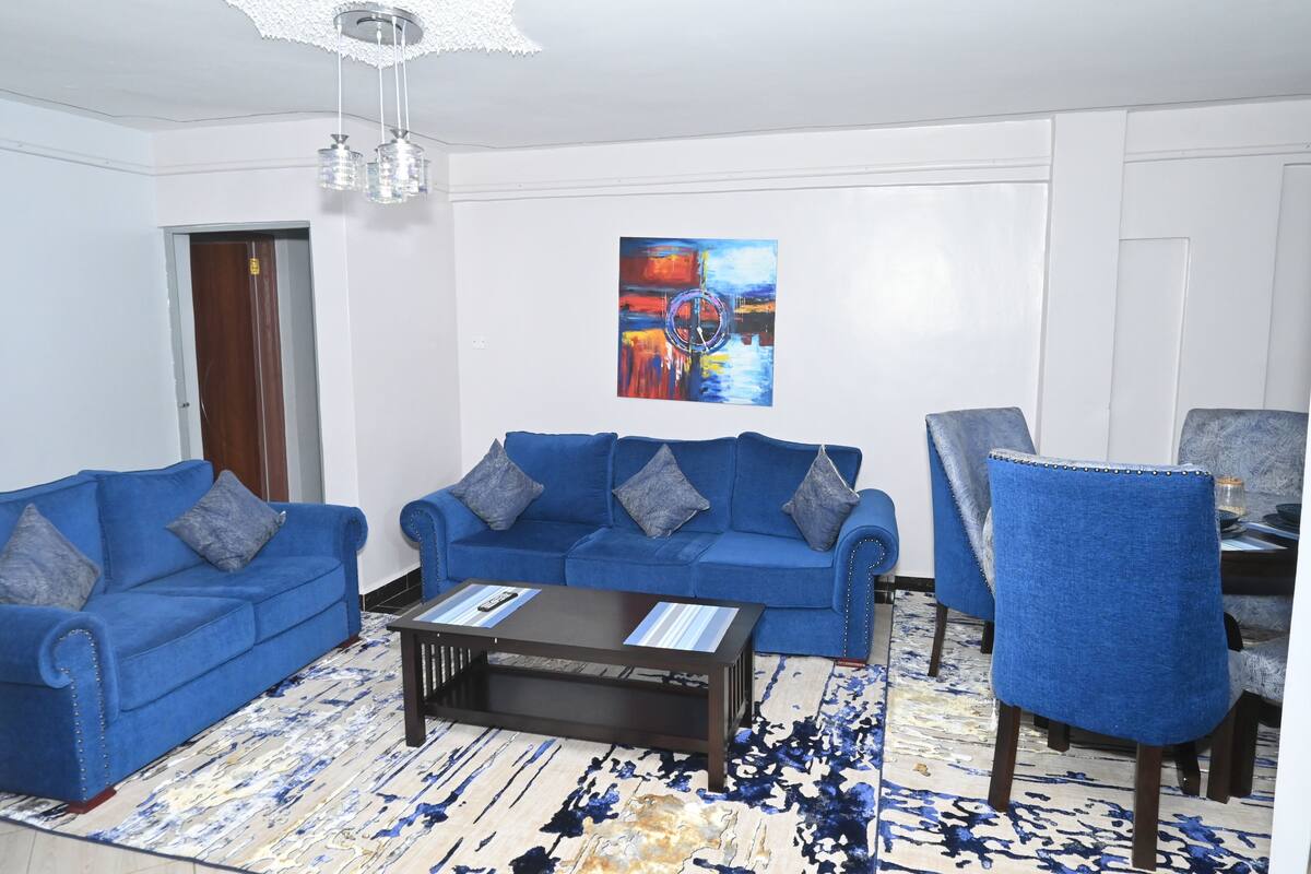Ein Wohnzimmer mit zwei blauen Sofas, einem Couchtisch und einem blauen Sessel.