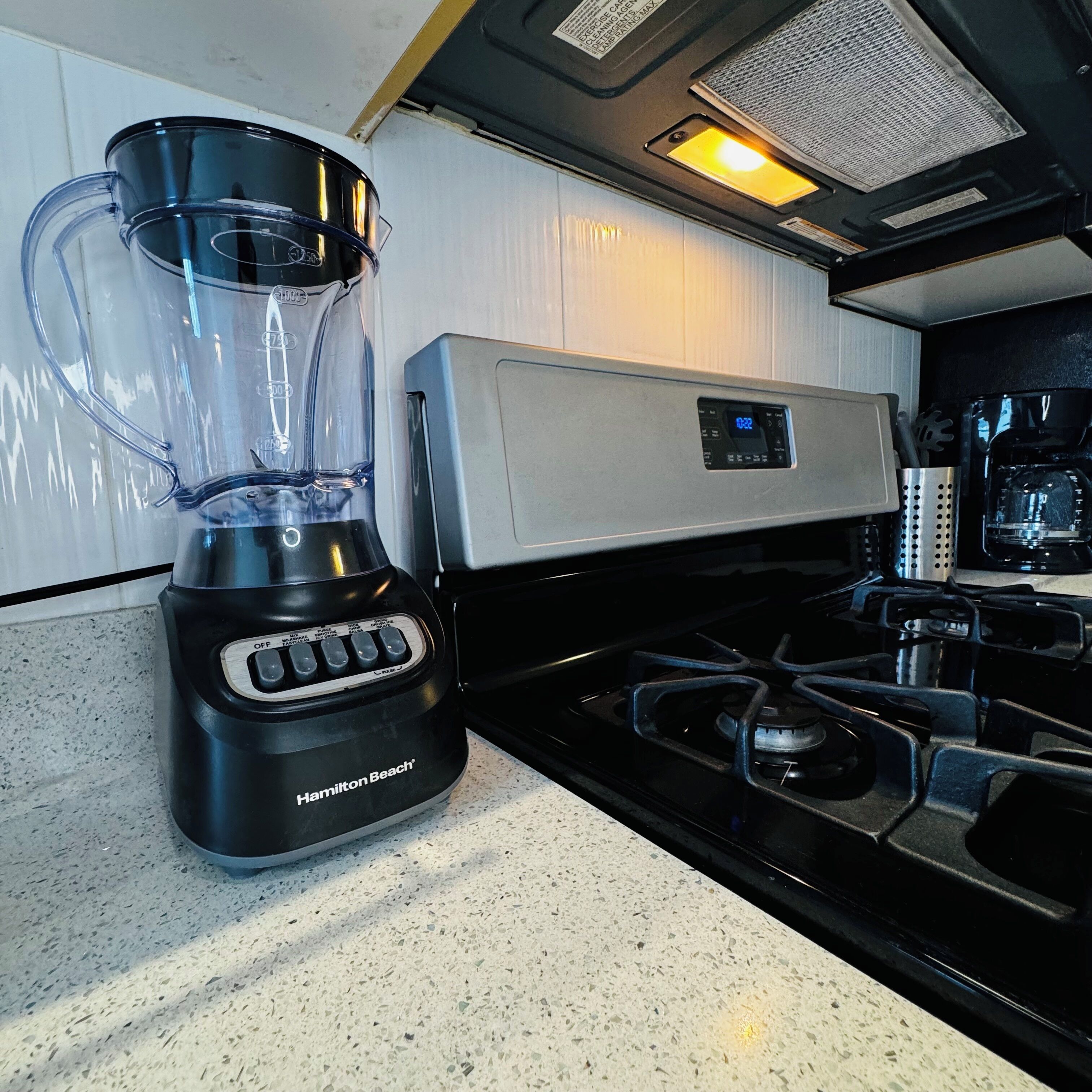Una cocina con una licuadora Hamilton Beach, una estufa y una cafetera.