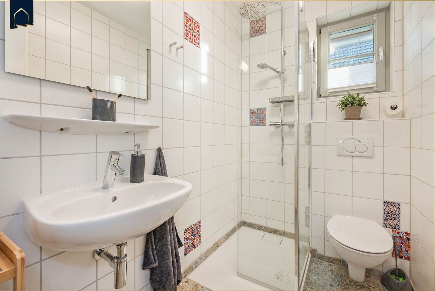 Une salle de bain moderne avec un lavabo blanc, une douche à parois de verre et des toilettes.