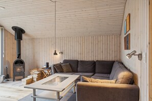 Une pièce chaleureuse avec un plafond en bois, un canapé, une table et une cheminée.