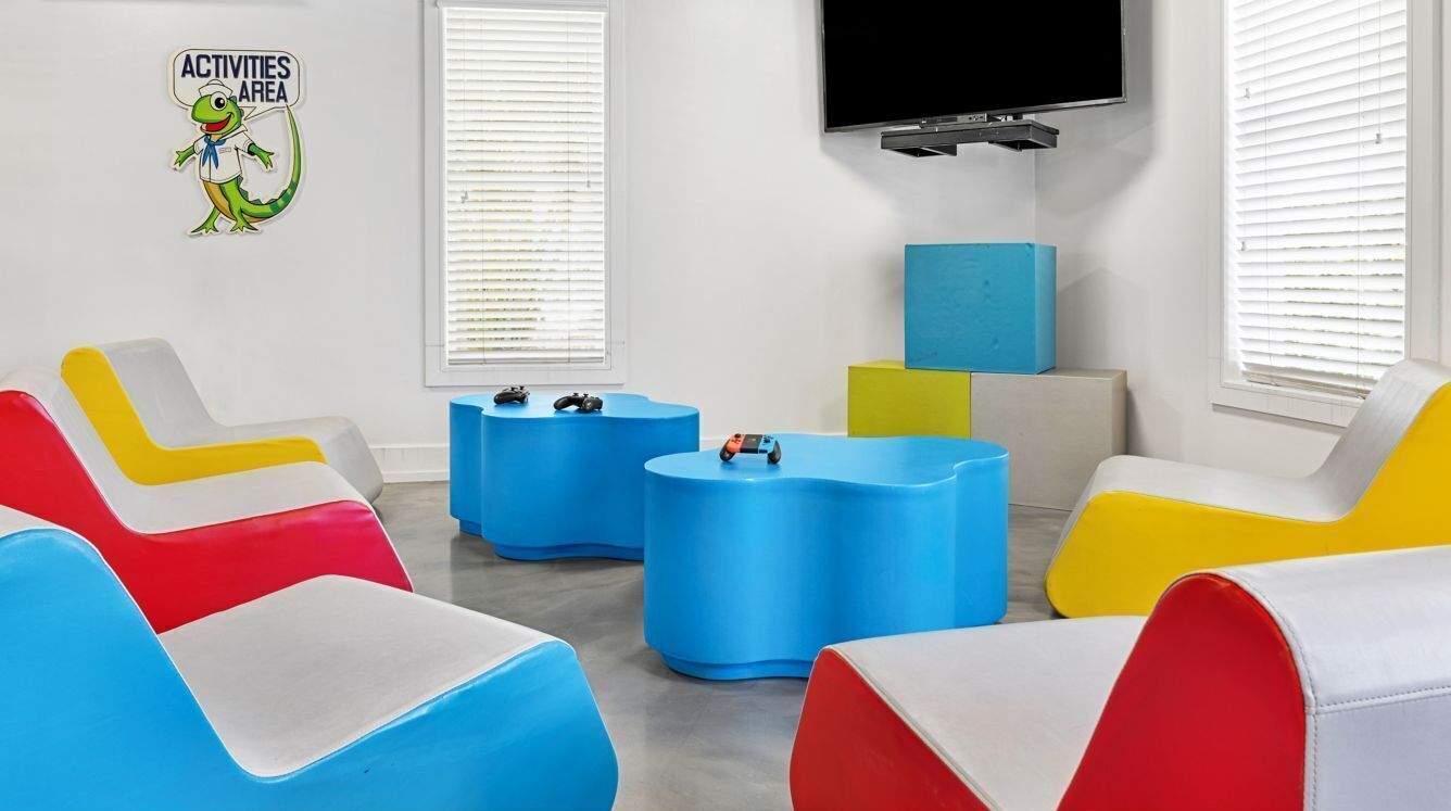 A room with colorful chairs, a TV, and a sign indicating an activities area.