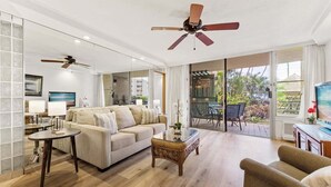 A spacious living room with a large window, a ceiling fan, and a view of the outdoors.