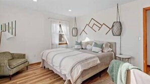 Um quarto com uma cama, uma cadeira e uma mesa de cabeceira.