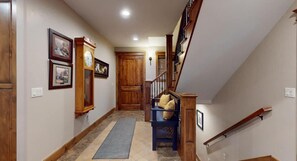 Un couloir avec un banc en bois, une porte et un escalier doté d’une rampe en bois.