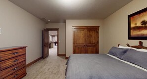 A bedroom with a bed, a dresser, a wardrobe, and a painting on the wall.