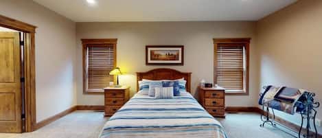 Un dormitorio con una cama, dos mesitas de noche, una lámpara, un cuadro en la pared y una ventana con persianas.