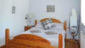 Een slaapkamer met een houten bed, een bedlampje, een spiegel en wanddecoraties.