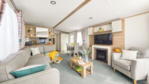 Uma sala de estar moderna com sofá, poltronas, mesa de centro, lareira e televisão.
