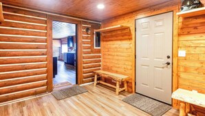 A log cabin interior with a wooden bench, a door, and a bench by the door. - Log Cabin in the Woods (Munising Township)