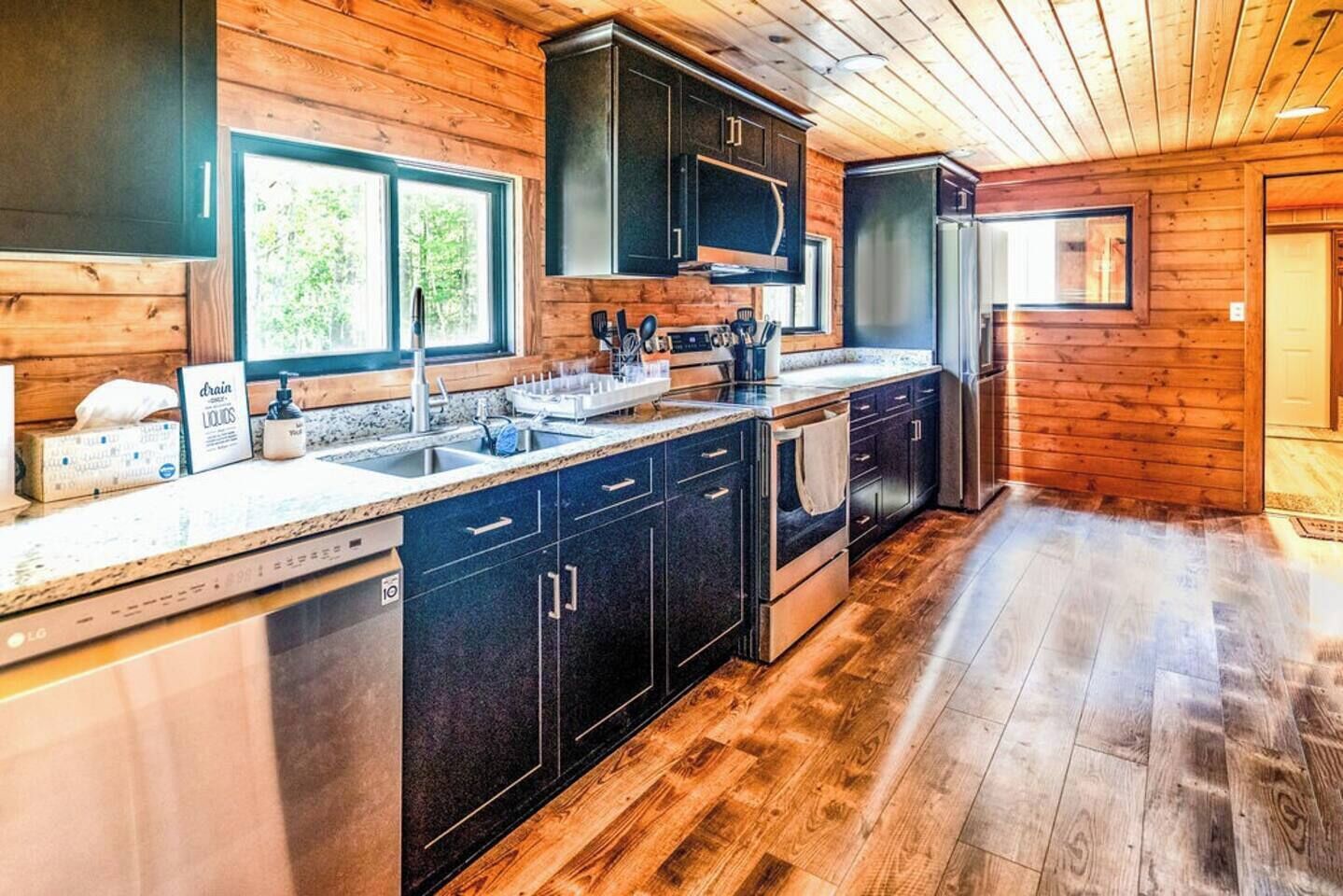 A modern kitchen with dark cabinetry, a stainless steel refrigerator, and a granite countertop.