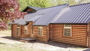 A log cabin with a metal roof, a front porch, and a small deck. - Log Cabin in the Woods (Munising Township)