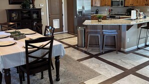 A modern kitchen with wooden cabinets, a stainless steel refrigerator, and a central island with bar stools.