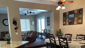 A spacious living area with a dining table, chairs, and a kitchen area with a countertop and sink.
