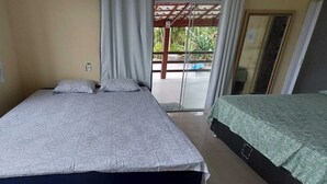 A room with a bed, a small table, and a view of the outdoors. - Quarto Para Grupo até 4 Pessoas Praia da Maranduba Ubatuba Sp (Sertão da Quina Ubatuba)