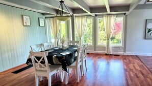 A dining area with a table set for six, surrounded by white chairs, with a black tablecloth featuring a floral pattern.