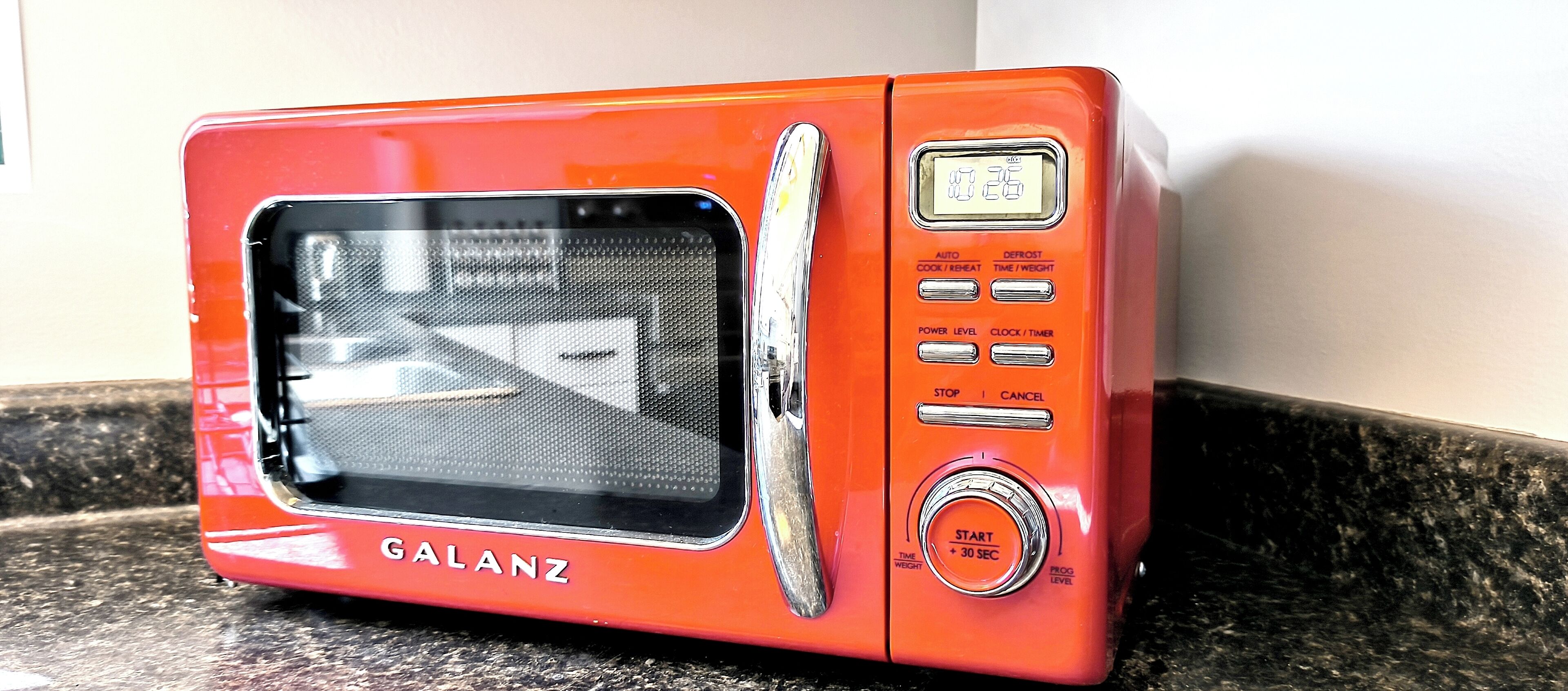 Un horno microondas Galanz rojo con pantalla digital, botones de control y una perilla de inicio/parada.
