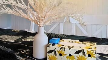 Un salon moderne avec un vase blanc, une boîte à motifs et une grande fleur posée sur un canapé noir et blanc à motifs.