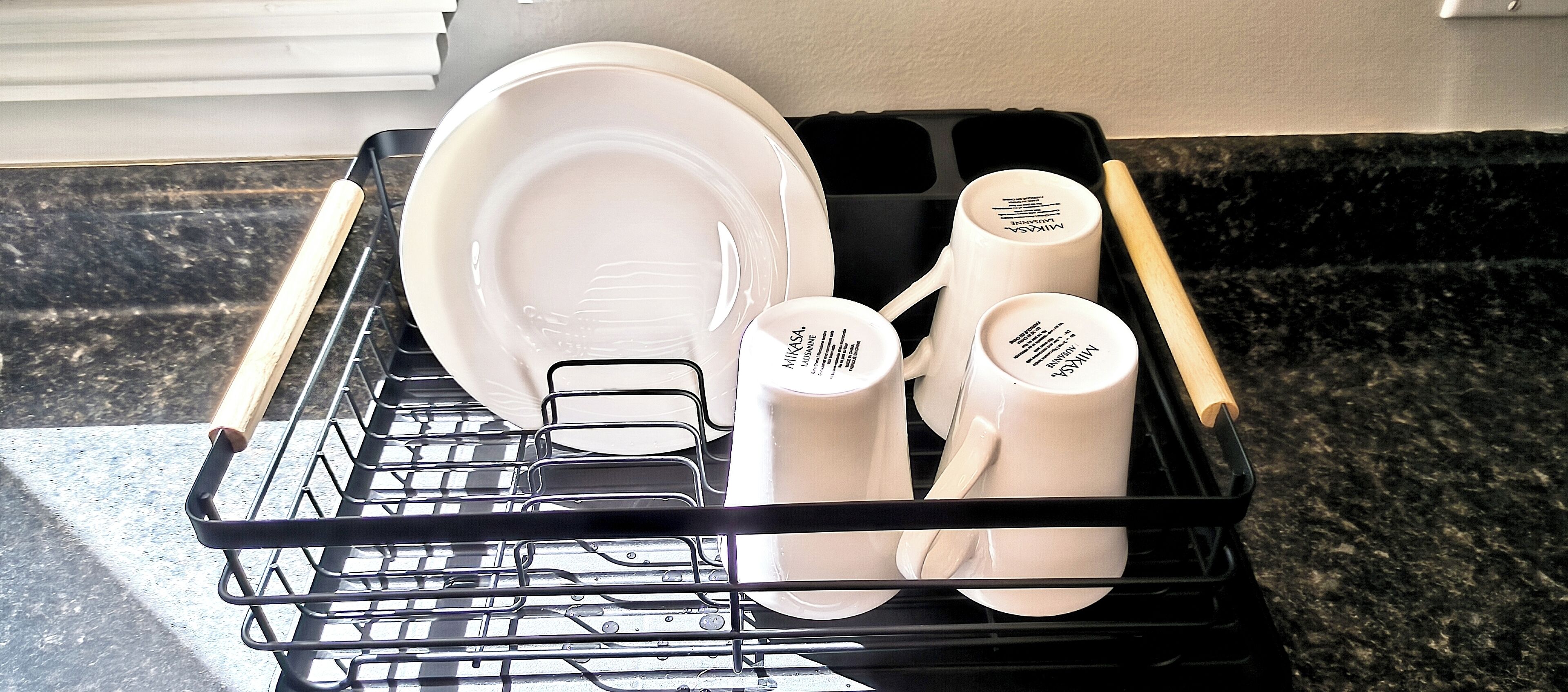 Un lave-vaisselle rempli d’assiettes, de tasses et de couverts blancs.
