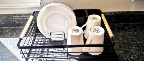 Un lave-vaisselle rempli d’assiettes, de tasses et de couverts blancs.