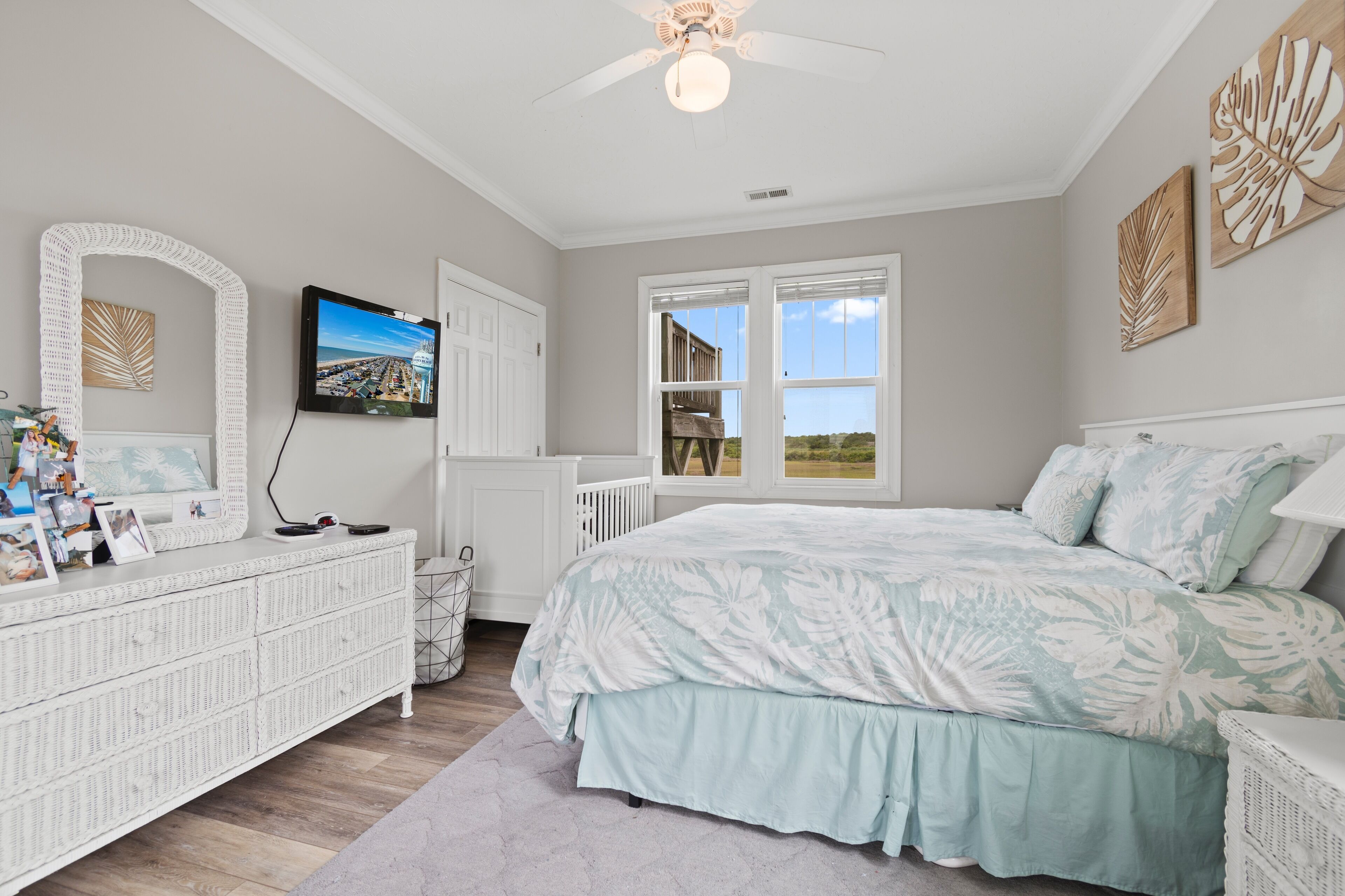 A bedroom with a large bed, a dresser, a TV, and a window with a view.