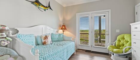 A bedroom with a bed, a nightstand, a lamp, a chair, and a door leading to a balcony.