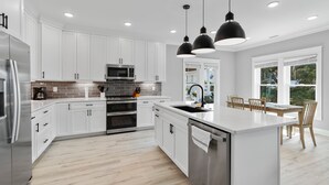 Una cocina moderna con armarios blancos, electrodomésticos de acero inoxidable y una isla grande.