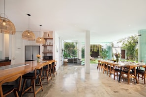 A modern kitchen with a wooden bar, bar stools, and pendant lighting.