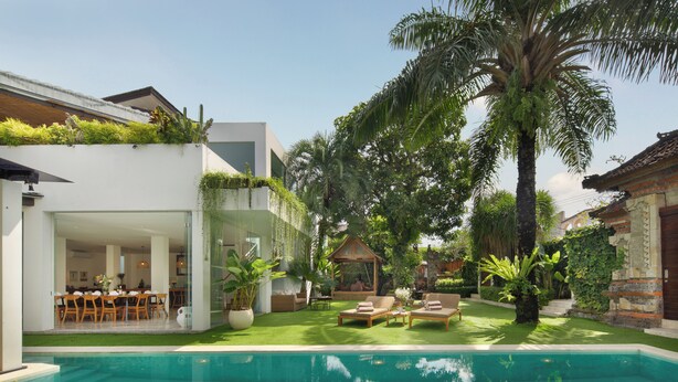 A modern house with a swimming pool, outdoor seating, and lush greenery.