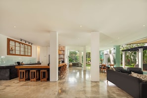A spacious open-plan living area with a kitchen, dining area, and a large window overlooking a garden.