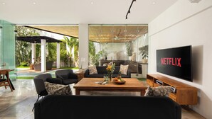 A modern living room with a flat-screen TV, a coffee table, and a sofa.