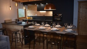 Een moderne keuken met houten details, een groot eiland met eettafel en een ingebouwde oven.