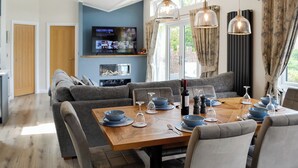 Ein modernes Wohnzimmer mit einem großen Fernseher, einem Esstisch für sechs Personen und einer gemütlichen Sitzecke.