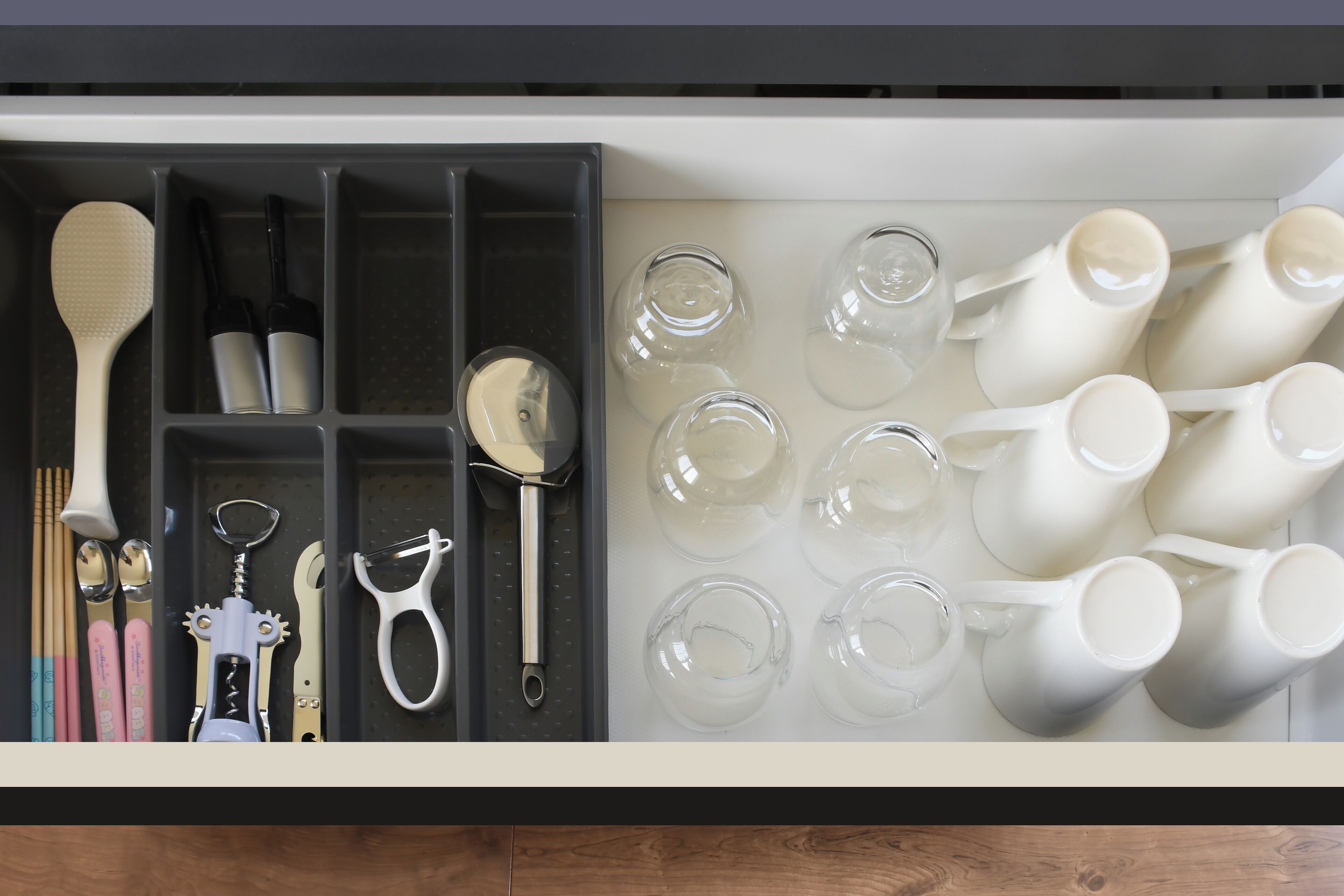 A kitchen drawer with utensils and glassware.