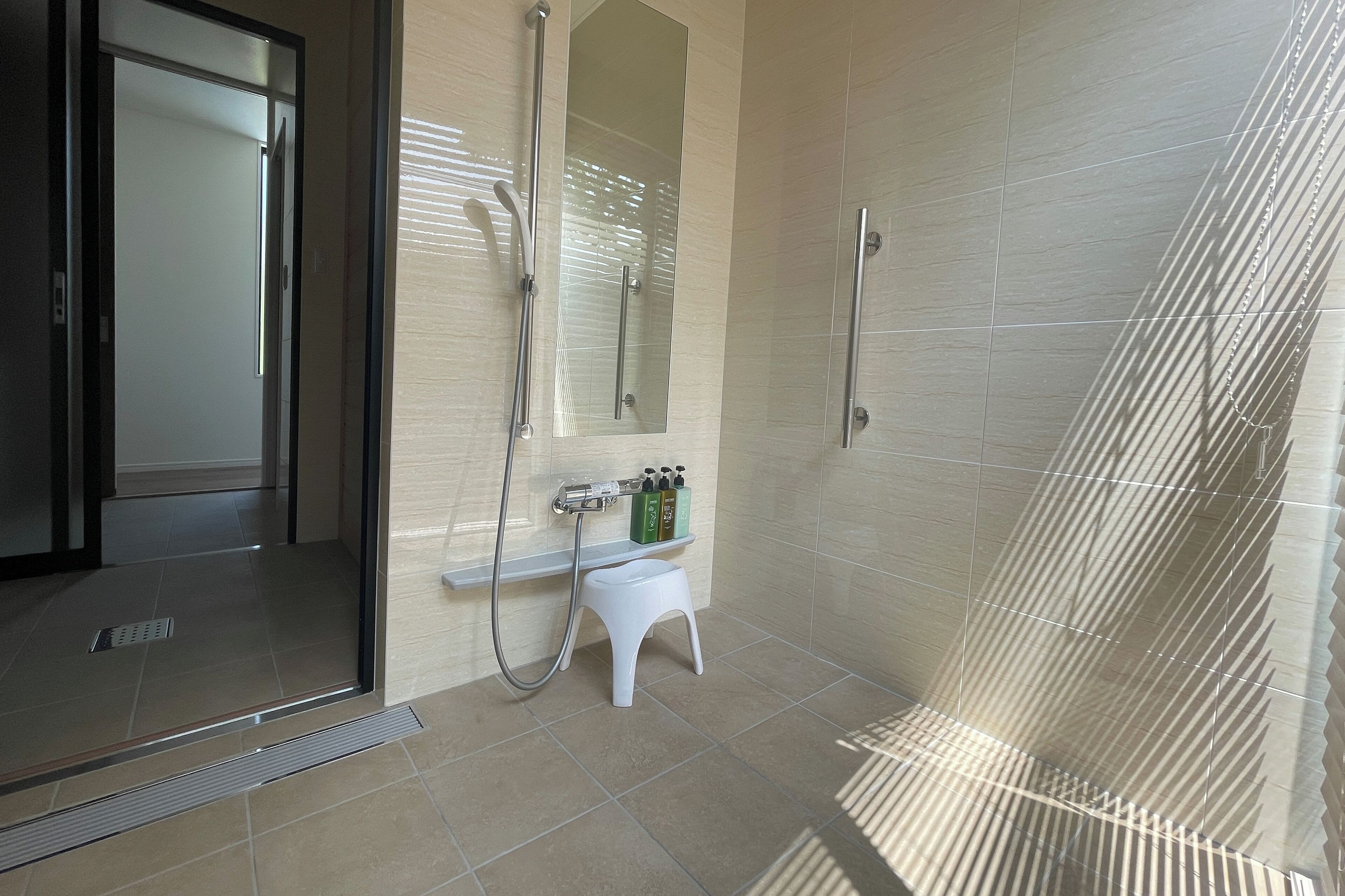A modern bathroom with a glass shower enclosure, a white pedestal sink, and a mirror.