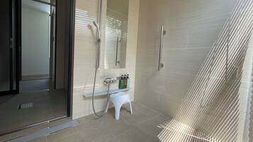 A modern bathroom with a glass shower enclosure, a white pedestal sink, and a mirror.