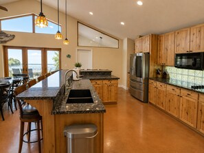 A modern kitchen with wooden cabinets, a stainless steel refrigerator, and a granite countertop.