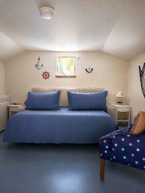 A bedroom with a bed, a nightstand, a lamp, and nautical-themed wall decorations.