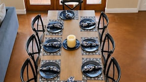 Una mesa de comedor preparada con platos negros, servilletas azules y una vela en el centro.