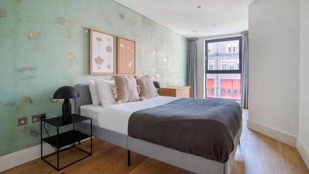 A modern bedroom with a bed, bedside table, lamp, and artwork on the wall. - Bright Aldgate 1BR, close to Train & Liverpool Street, by Blueground (London)