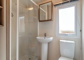 A bathroom with a glass-enclosed shower, a pedestal sink, and a toilet. - Castaways Oyster 10 (Pet) (Bacton-on-Sea)