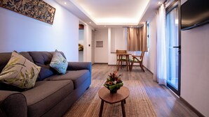 Una sala de estar moderna con un sofá, una mesita redonda con un arreglo floral y un comedor con una mesa y sillas.