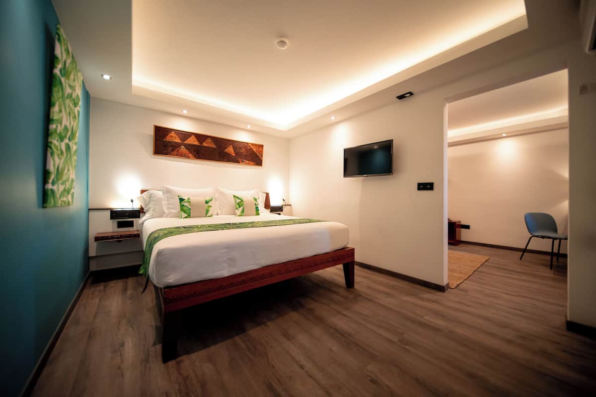 A modern bedroom with a bed, bedside tables, a flat-screen TV, and a wall-mounted artwork.