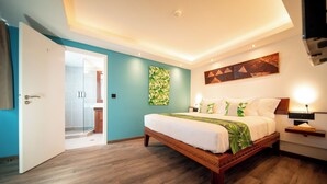 Un dormitorio moderno con una cama de madera, ducha de vidrio, paredes color aguamarina y una obra de arte geométrica en la pared.