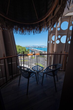 Enjoy the serene marina views and mountain vistas from this balcony with a thatched roof and comfortable seating area.