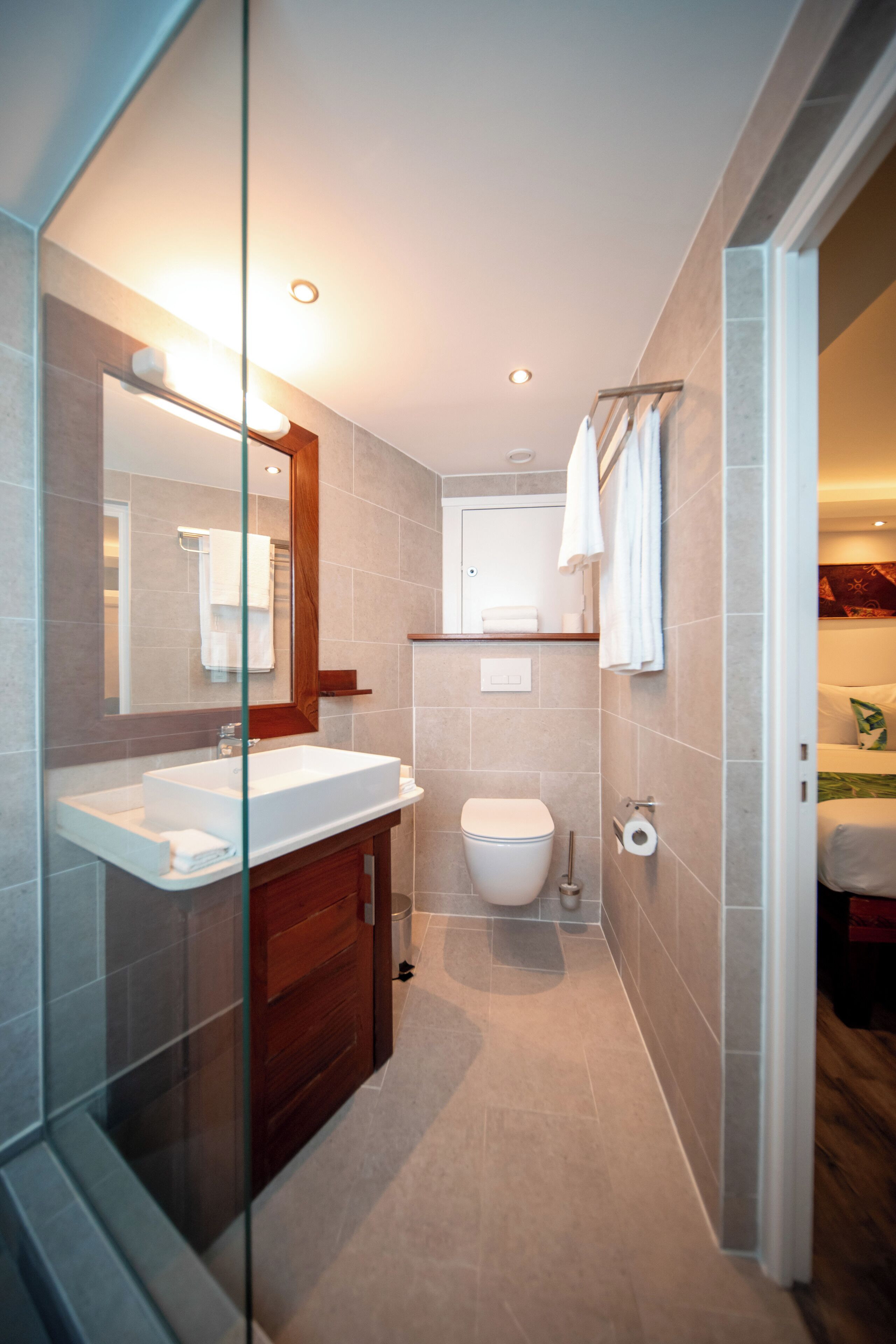 A modern bathroom with a glass shower enclosure, a white sink, and a wooden vanity.