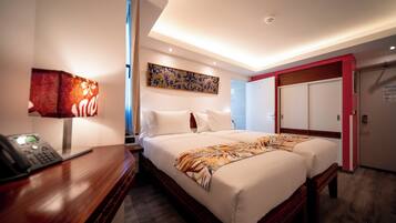 Habitación de hotel con una cama grande, un escritorio con teléfono, un cuadro en la pared y una puerta que da a otra habitación.