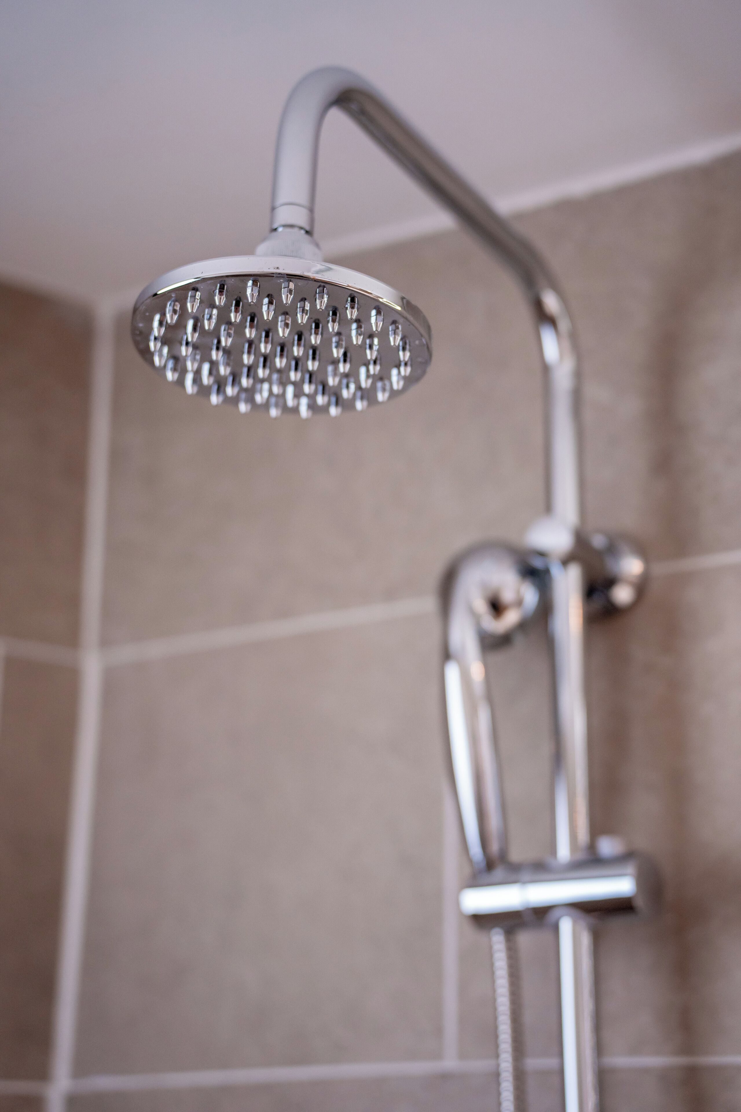 A showerhead with multiple nozzles, a curved shower arm, and a control knob.