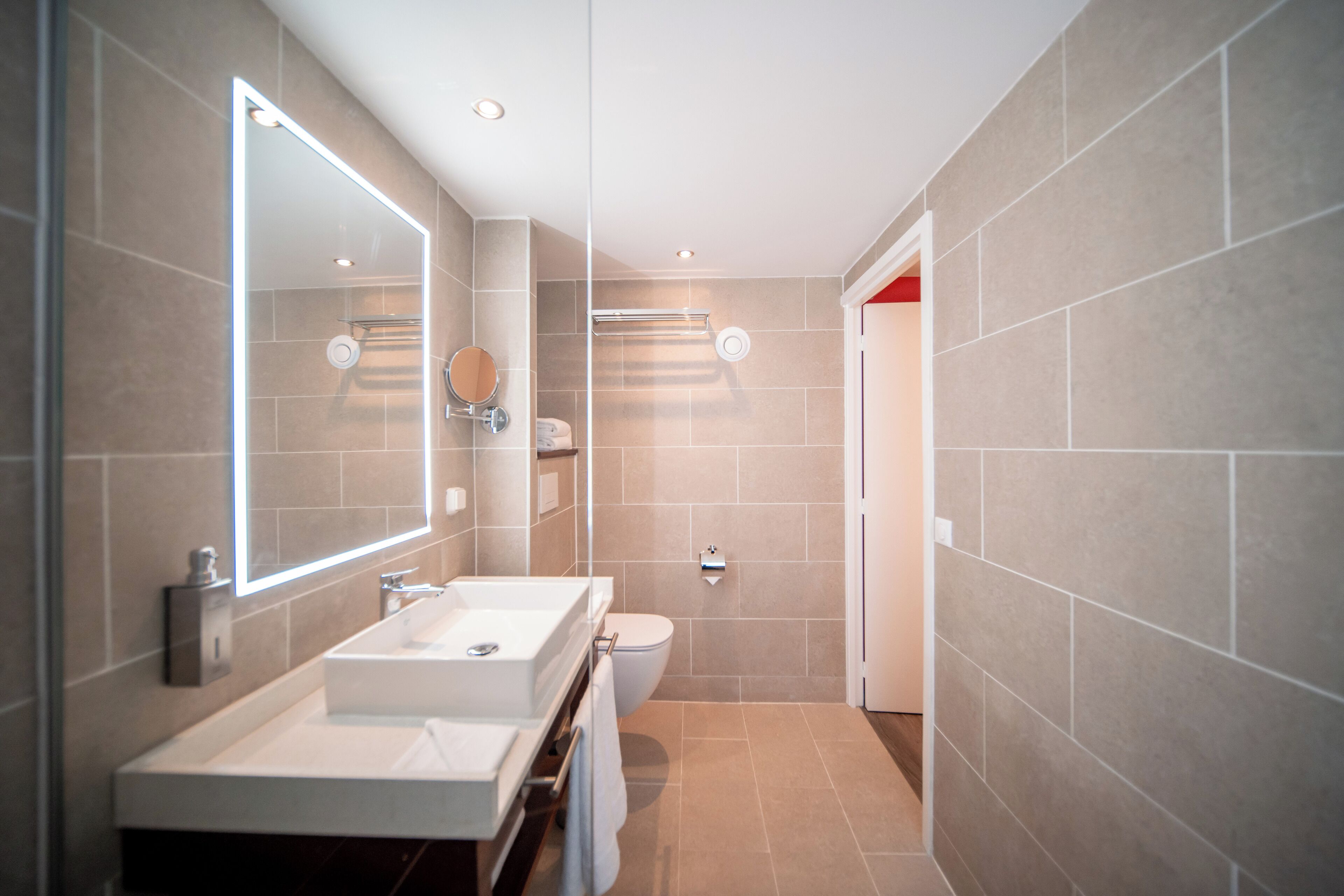 Un baño moderno con dos lavamanos, un espejo grande y una zona de ducha.